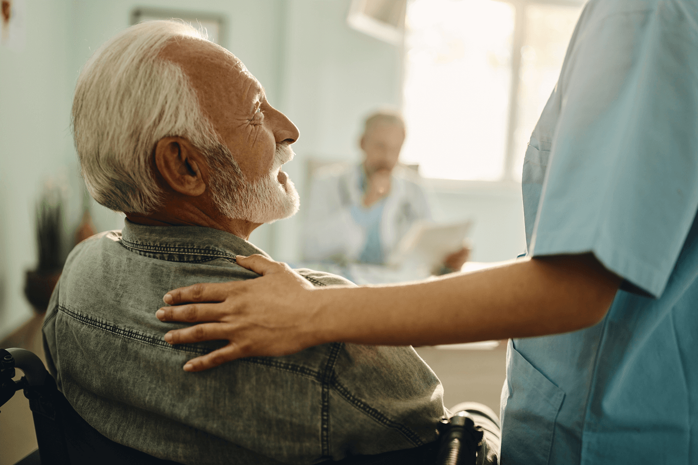 A senior man in a wheelchair talks with a nurse