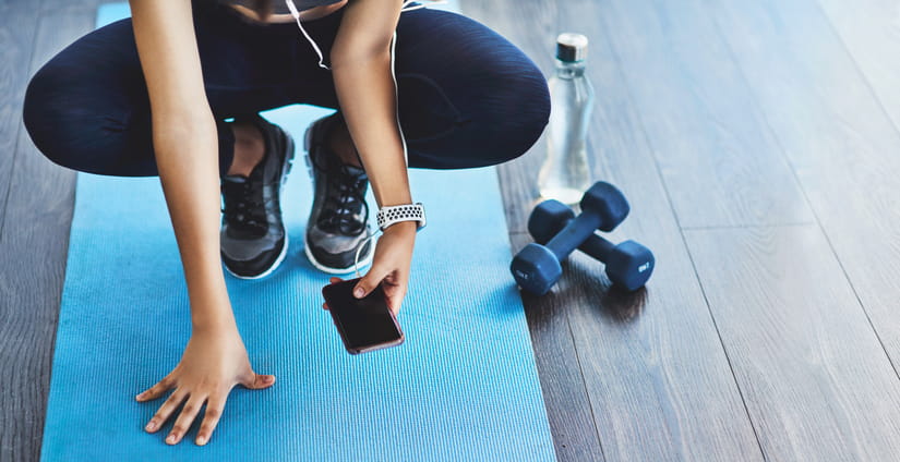 A woman checking her phone on a yoga mat