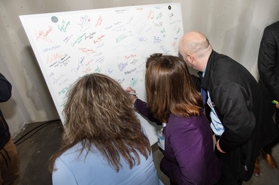 Geisinger employees add their signature to the piece of wall at Geisinger Cancer Center Dickson City