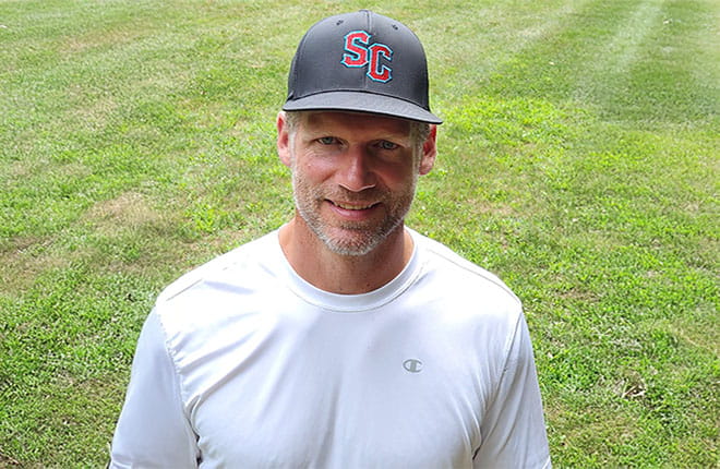 Rob Campbell stands outside in a freshly-mowed field of grass.