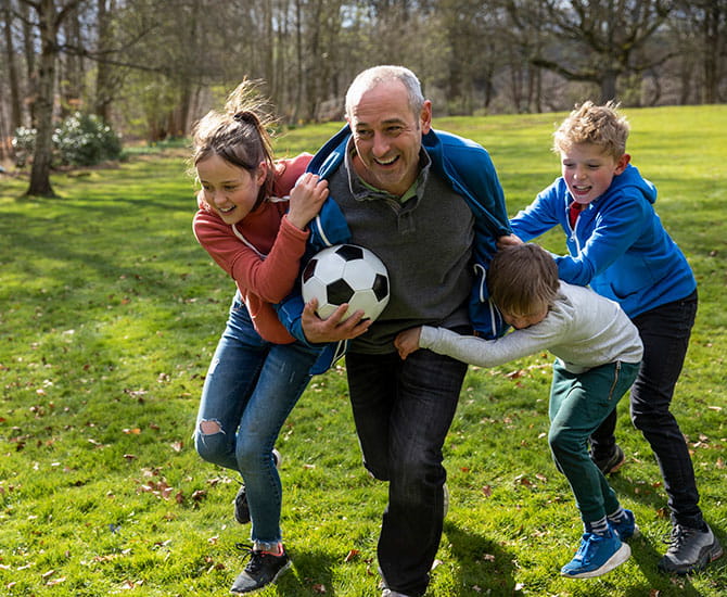 An older gentlemen playing soccer with kids
