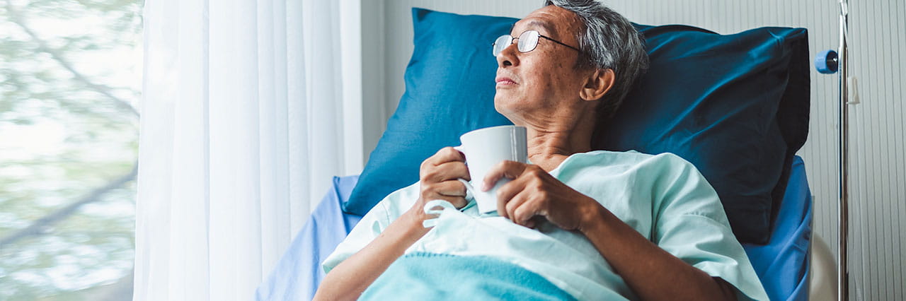 Cancer patient looking out of the window in his hospital bed