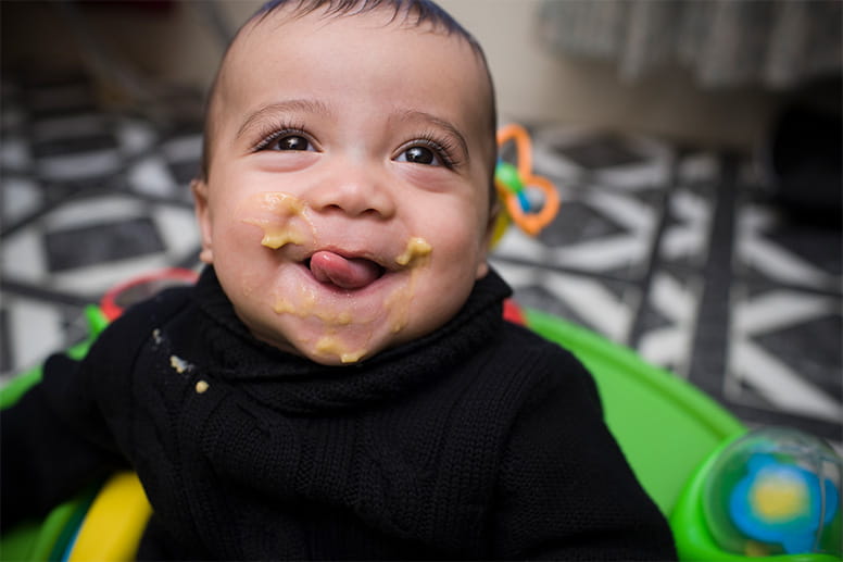 Adorable Hispanic Baby Boy Eating in High Chair
