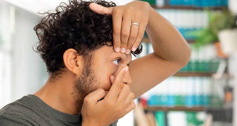 a man putting contacts into his eye at a optical center
