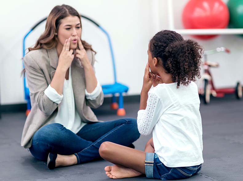 a female speech therapist helping a young girl