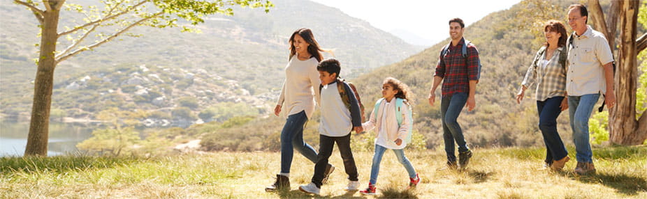 Multi generation family enjoying a hike by a mountain lake