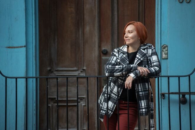 Woman looking off in the distance standing in front of a door