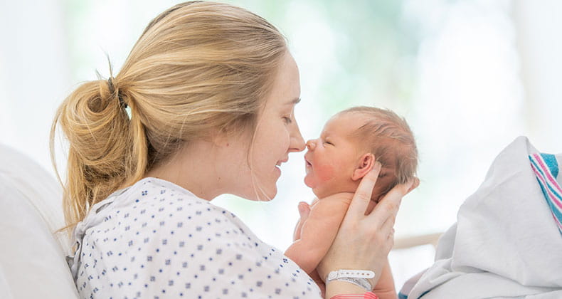 a woman holding her baby in a hospital bed after delivery