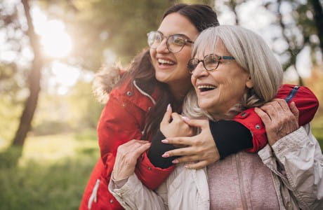 an older woman and younger woman hugging and smiling in nature