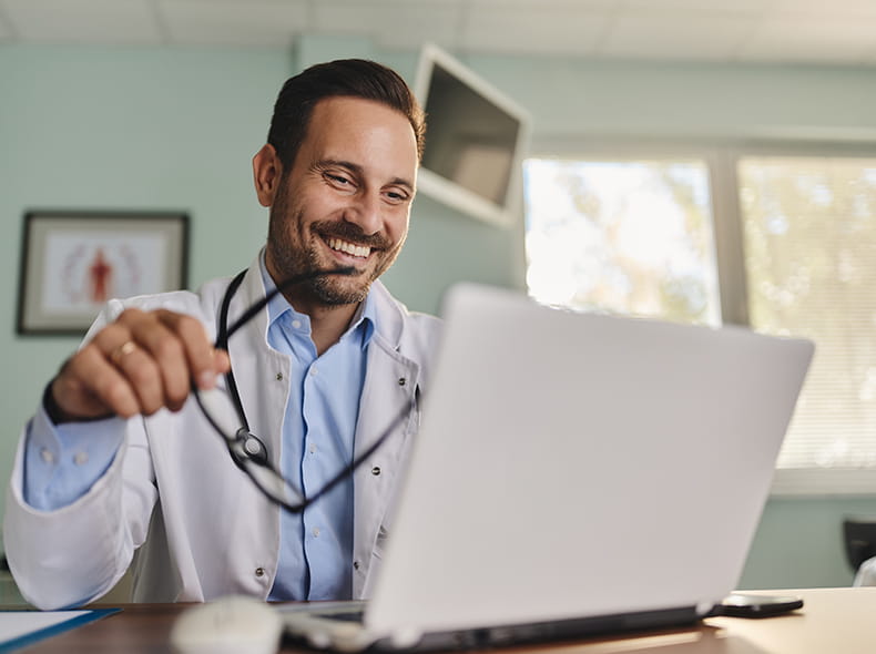 A smiling provider working on a laptop computer