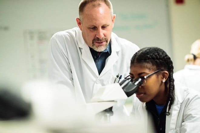 Doctors looking through microscope doing research for medicine