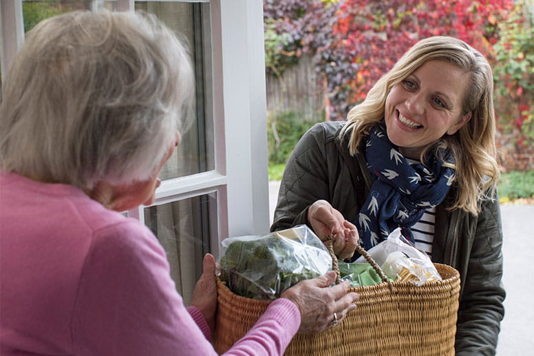 Female Neighbor Helping Senior Woman With Shopping