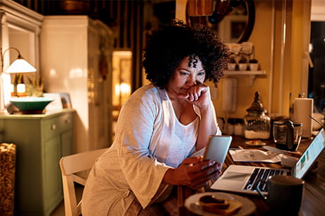 Woman at home on computer about to make a phone call