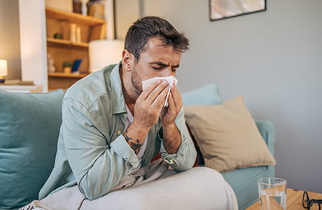 A sick mid adult man is sitting on a sofa.