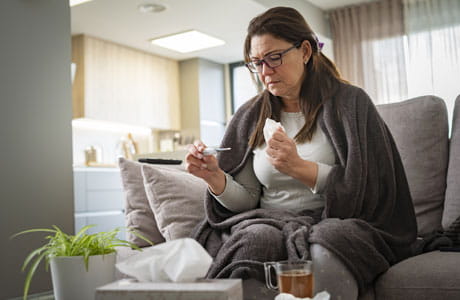 A sick woman reading a thermometer