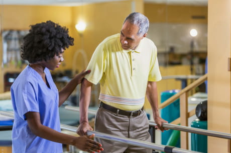 Man walks with assistance in physical therapy