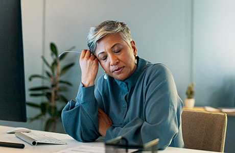 Woman sitting down having a stress headache.