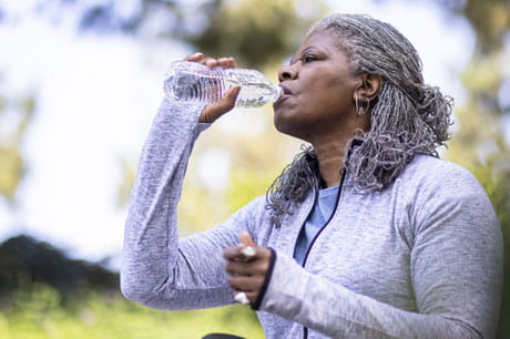 A woman drinking an 8 ounce bottle of water.