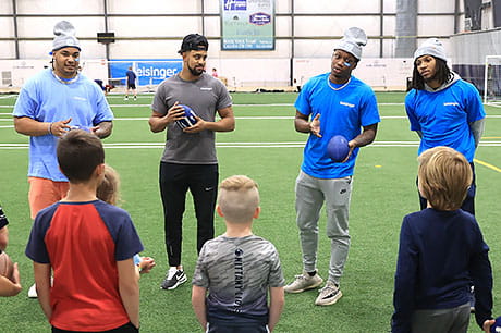 Football players Dvon Ellies, Keaton Ellis, Kalen King and Daequan Hardy at a football clinic for local youth.