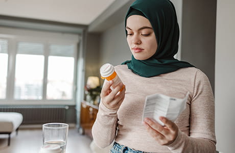 Woman reading prescription bottle. 