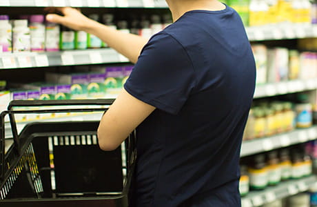Hand reaching into vitamin and medicine shelf