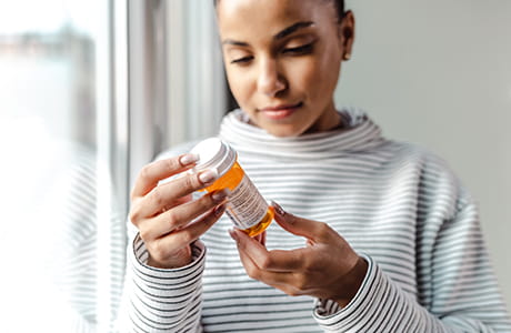 A woman looking at a medicine bottle