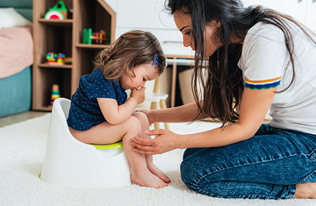 A mom potty training her child on the toilet