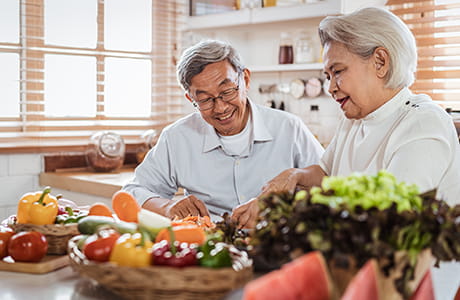 Senior Asian couple love cooking together in the kitchen with happiness