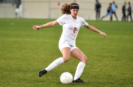 A woman kicking a soccer ball.