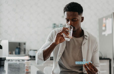 Young man taking medication with water.