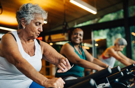 Women working out as one woman checks her blood pressure on her watch.