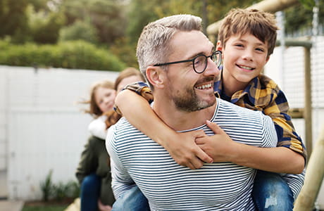 A father holds his son on his back smiling and enjoying the outdoors