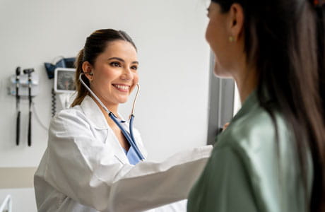 A doctor discusses aortic stenosis with a smiling female patient.