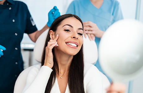 A woman looks at herself in the mirror at a medical office after receiving botox