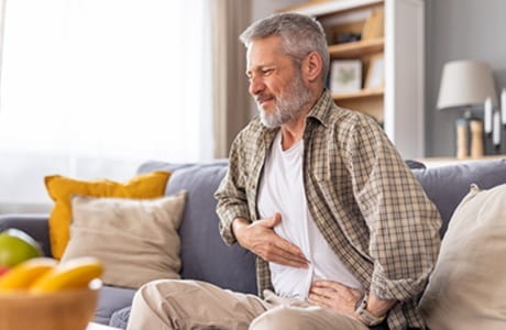 A man having troubles with acid reflux clutches his stomach