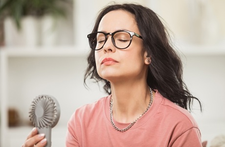 A woman cooling off by using a hand held fan