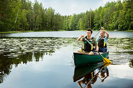 Two men paddle in a canoe, helping them age well by building their friendship and being active.