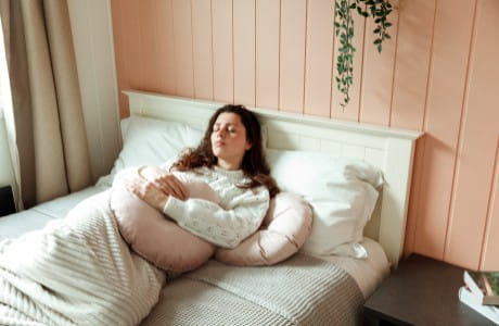Young woman in bed with abdominal discomfort