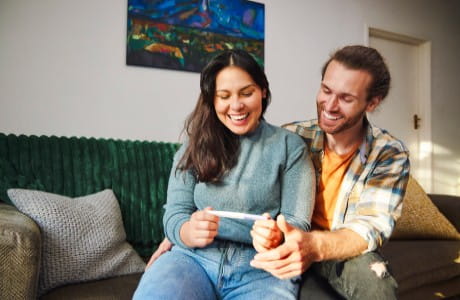 Young couple looking joyfully at positive pregnancy test