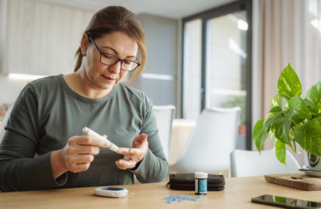Person checking blood sugar levels at home using a glucose meter and test strips, illustrating prediabetes monitoring and diabetes management.