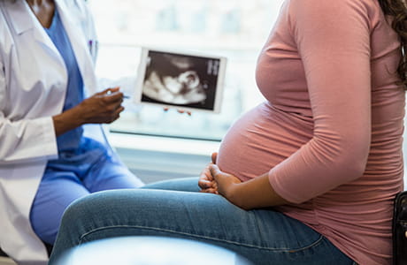 Pregnant patient meeting with a healthcare provider to review prenatal ultrasound results and discuss genetic counseling during pregnancy.