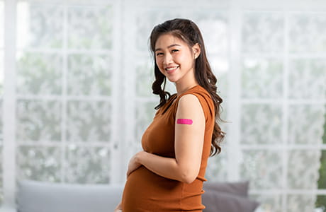 Happy pregnant woman shows off band aid from flu shot