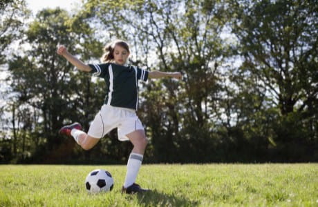 Young girl kicks soccer ball