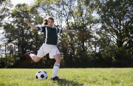 Young girl kicks soccer ball