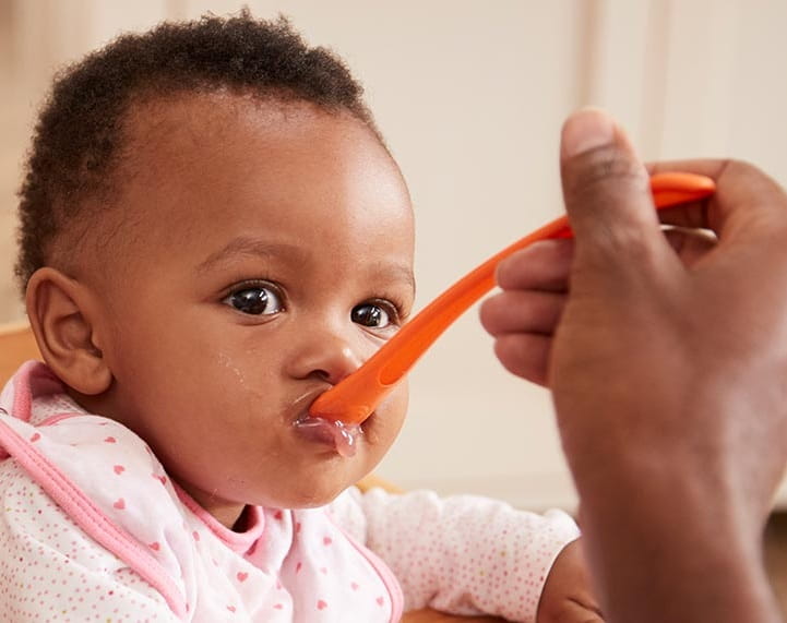 A small child being fed by their parent