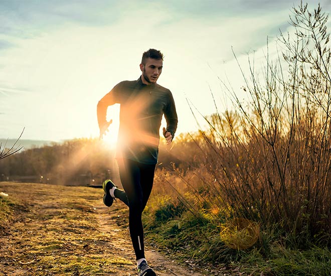 man running with sunset behind him