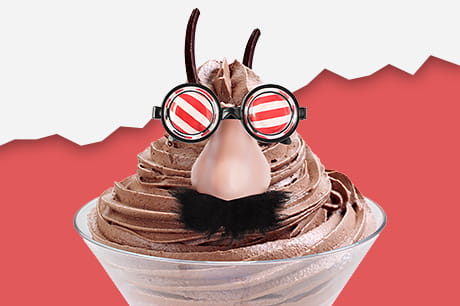 A chocolate mousse dessert in a glass cup decorated with novelty glasses, a fake nose, and a mustache.