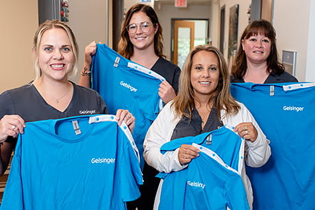 A group of Geisinger nurses holding up blue shirts.