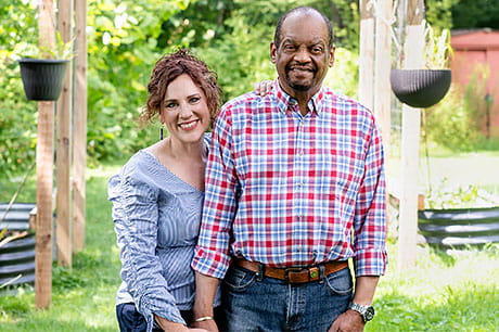 Two people standing together outdoors in a garden setting, representing support and recovery.
