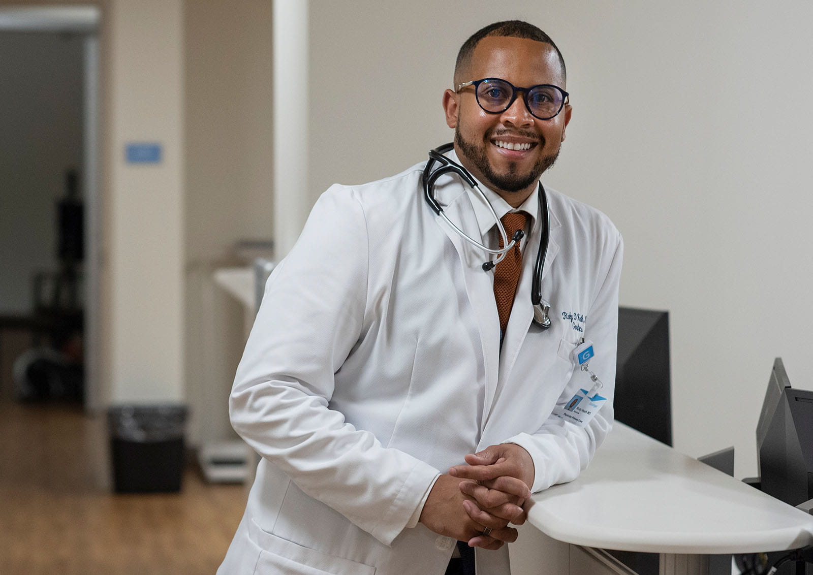 Healthcare provider standing at a nurses' station in a clinical setting.